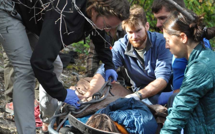 four people participate in a wilderness first responder exercise